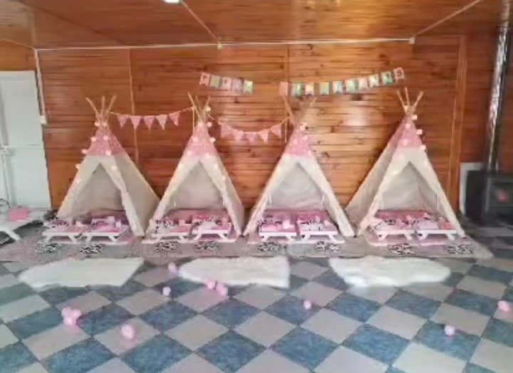Cuatro carpas tipi rosadas montadas en fila con alfombras blancas y globos en el piso