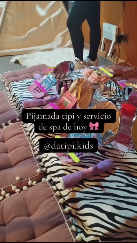 Estación de spa sobre manta de cebra con espejos, limas, flores y cojines